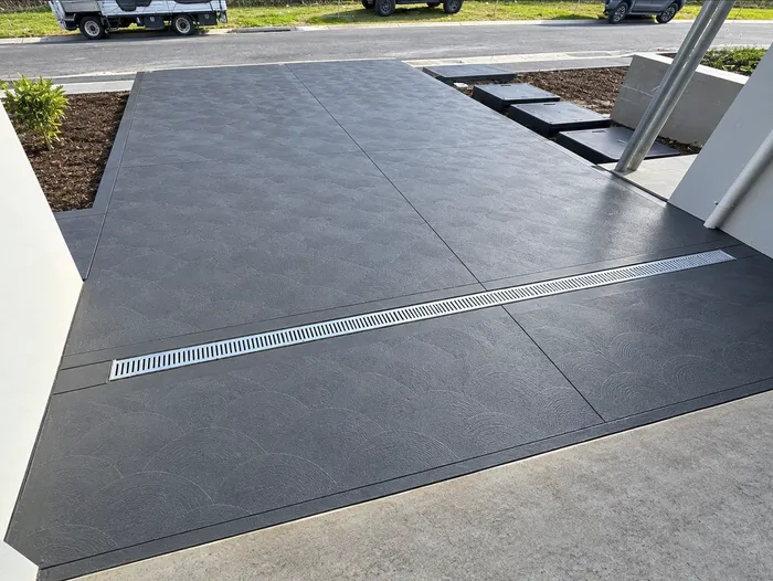 Charcoal coloured concrete driveway with a drainage channel