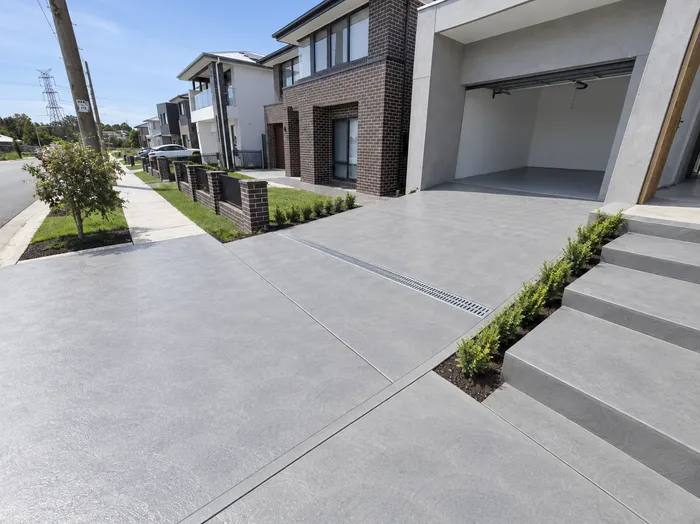 Plain concrete driveway leading to a two-storey home in Sydney