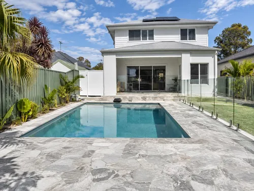 Travertine-tiled pool surround on a concrete base at a home in Caringbah, NSW