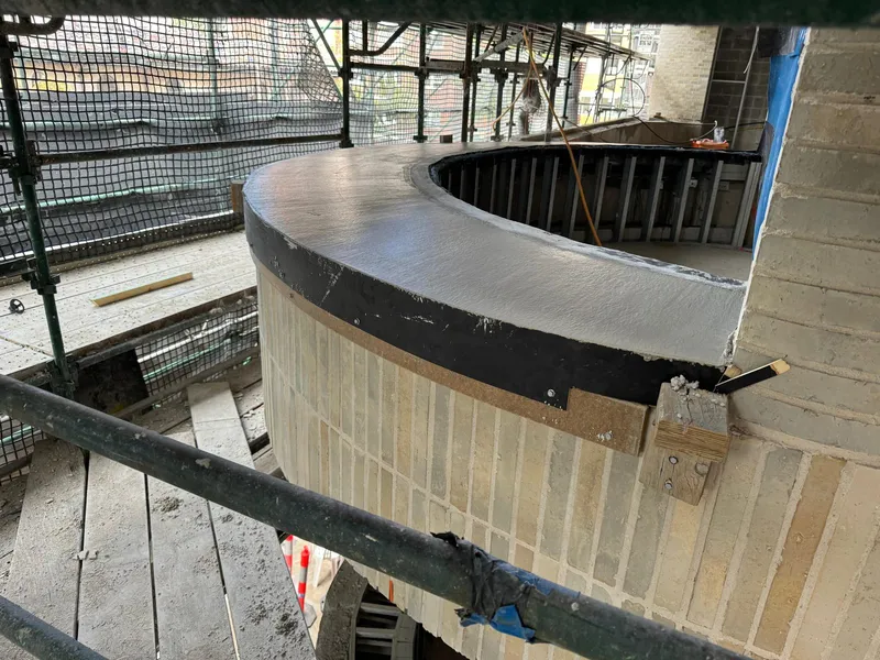 Close detail of a curved sill edge and the travertine panel below it