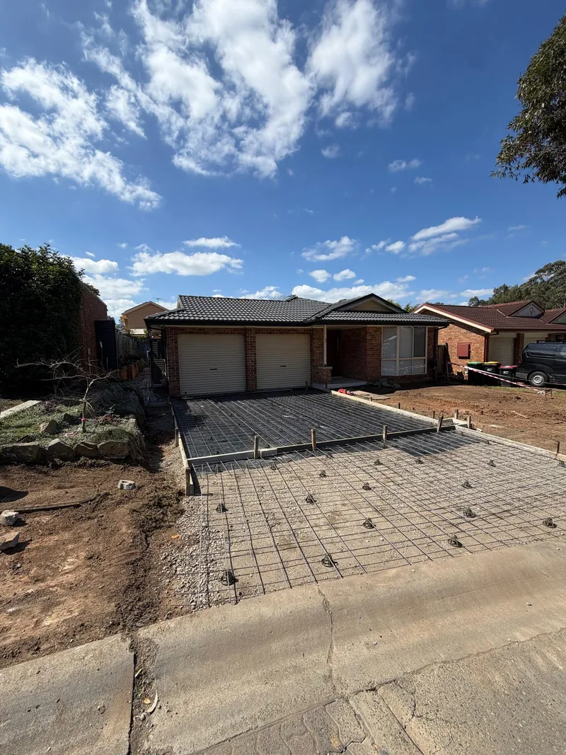 The new exposed aggregate concrete freshly poured in the backyard, matching the driveway