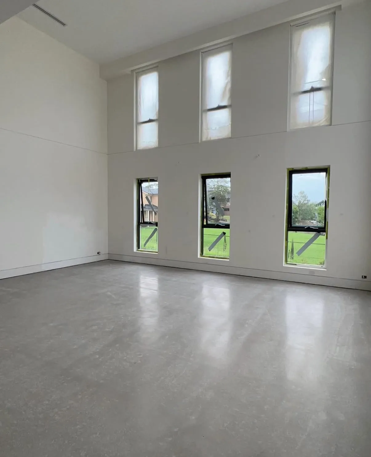Burnished concrete floor inside a double-height living space in Horsley Park, NSW