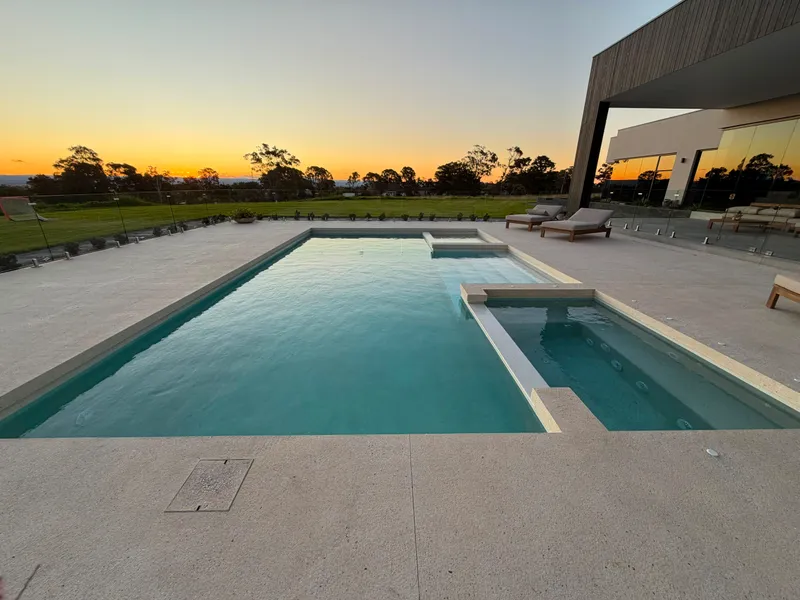 Pool and spa at Horsley Park looking out over the lawn at sunset, with the exposed aggregate surround in the foreground