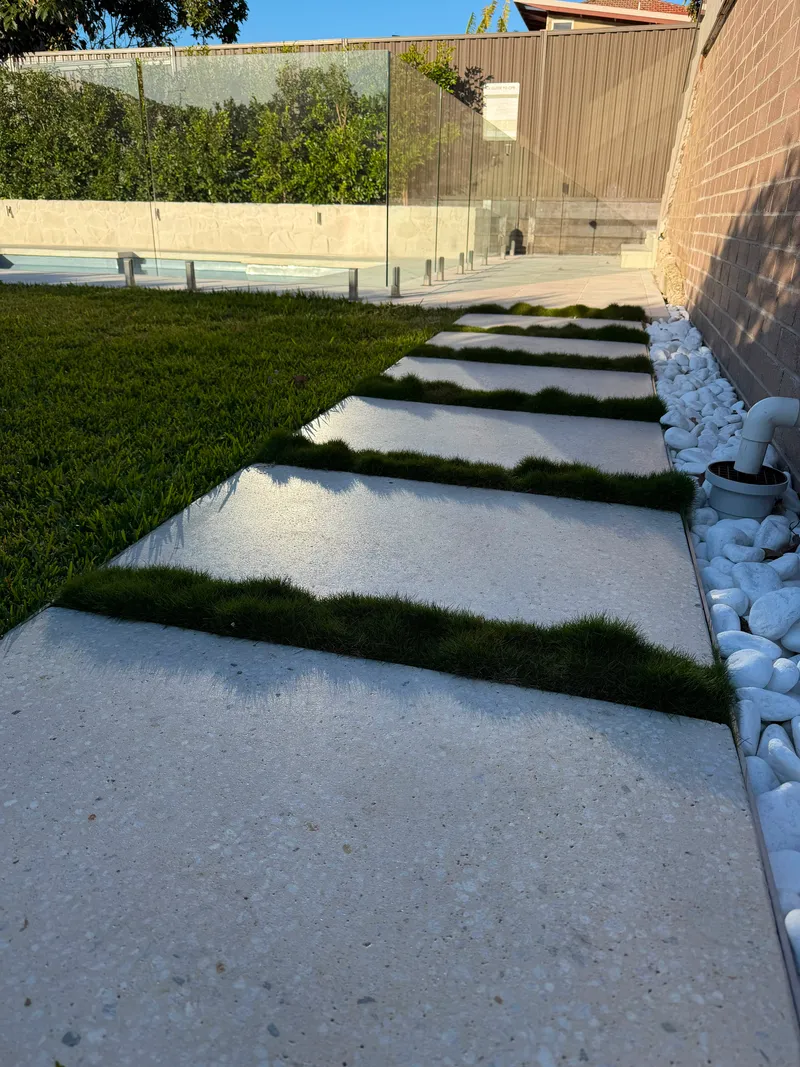 Honed concrete stepping stones set into the lawn at Matraville, running towards the pool