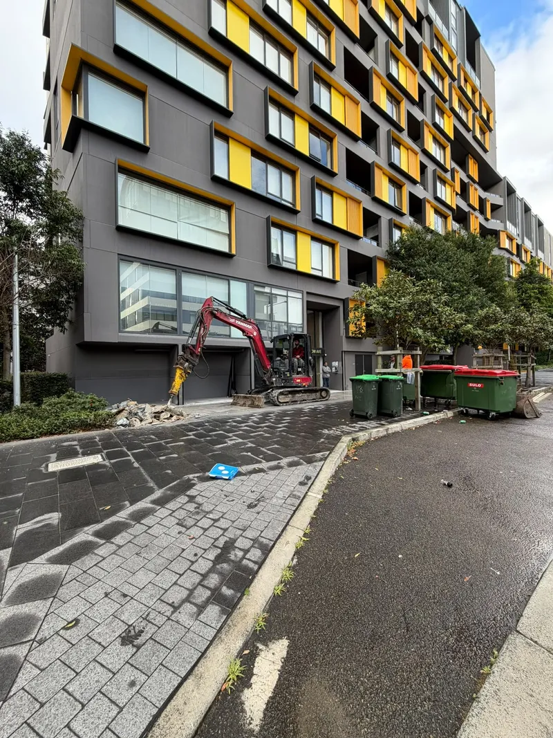 The excavator breaking out the old tiles at the 60 Nancarrow Ave entrance, with bins and the rubble pile alongside