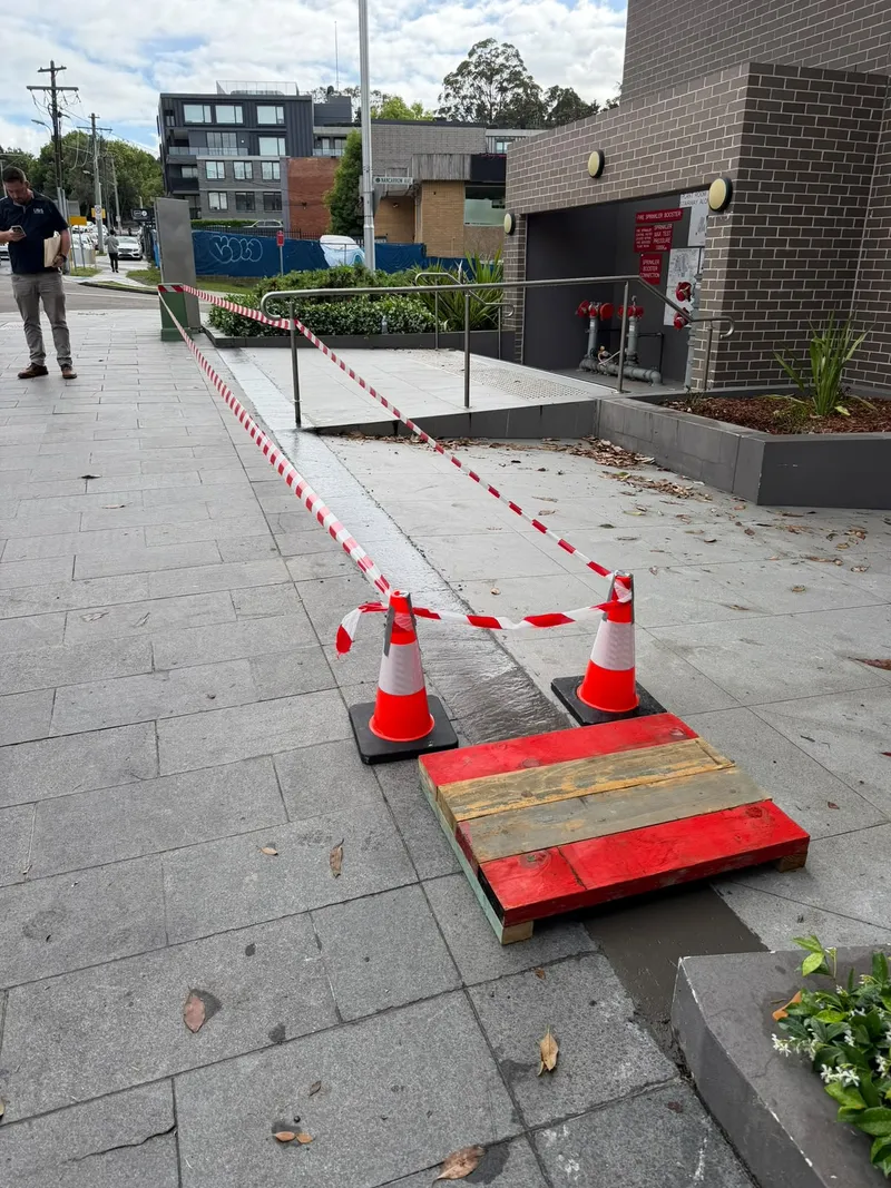 The taped-off side path at the fire sprinkler booster room before the old paving there was replaced